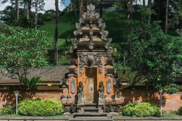 Entrance of ancient buddhist temple on hill surrounded by green trees on sunny day