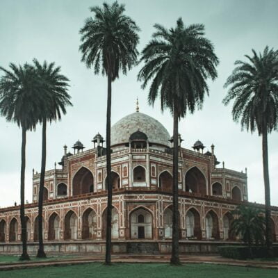 Low angle of beautiful well maintained garden with palms and ancient building of Humayun s Tomb located in Delhi